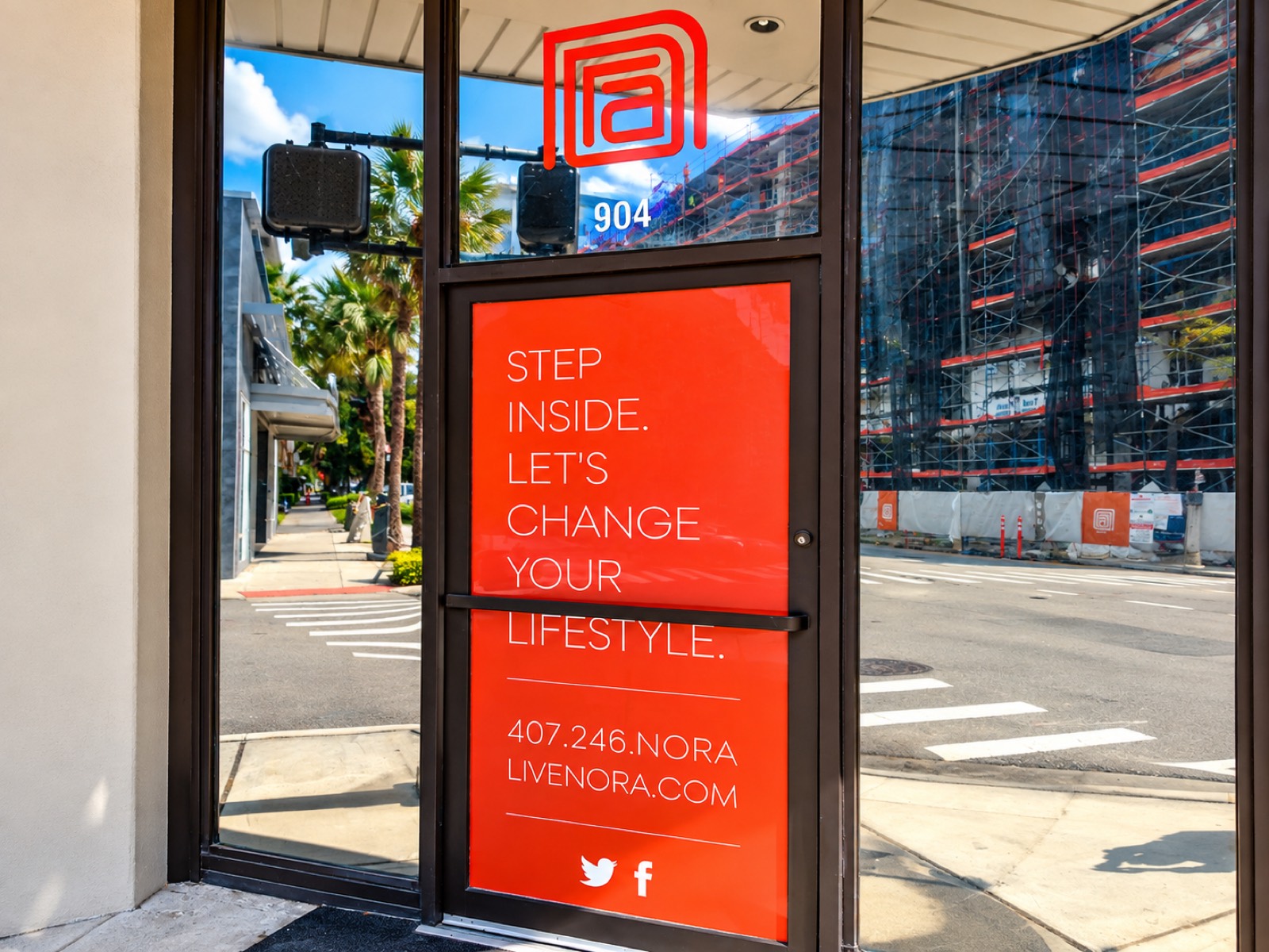 A red window graphic on a glass storefront door reading Step Inside